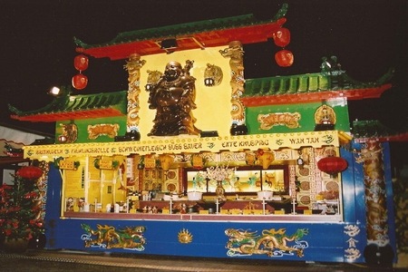 Imbisswagen beleuchtet bei Nacht mit Buddha, Drachen, Lampions und mehr