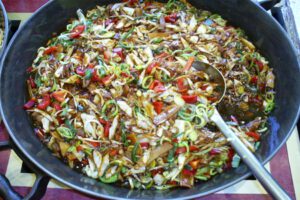 Buntes chinesisches Gericht mit Bambus, Paprika und Lauch in großer Pfanne